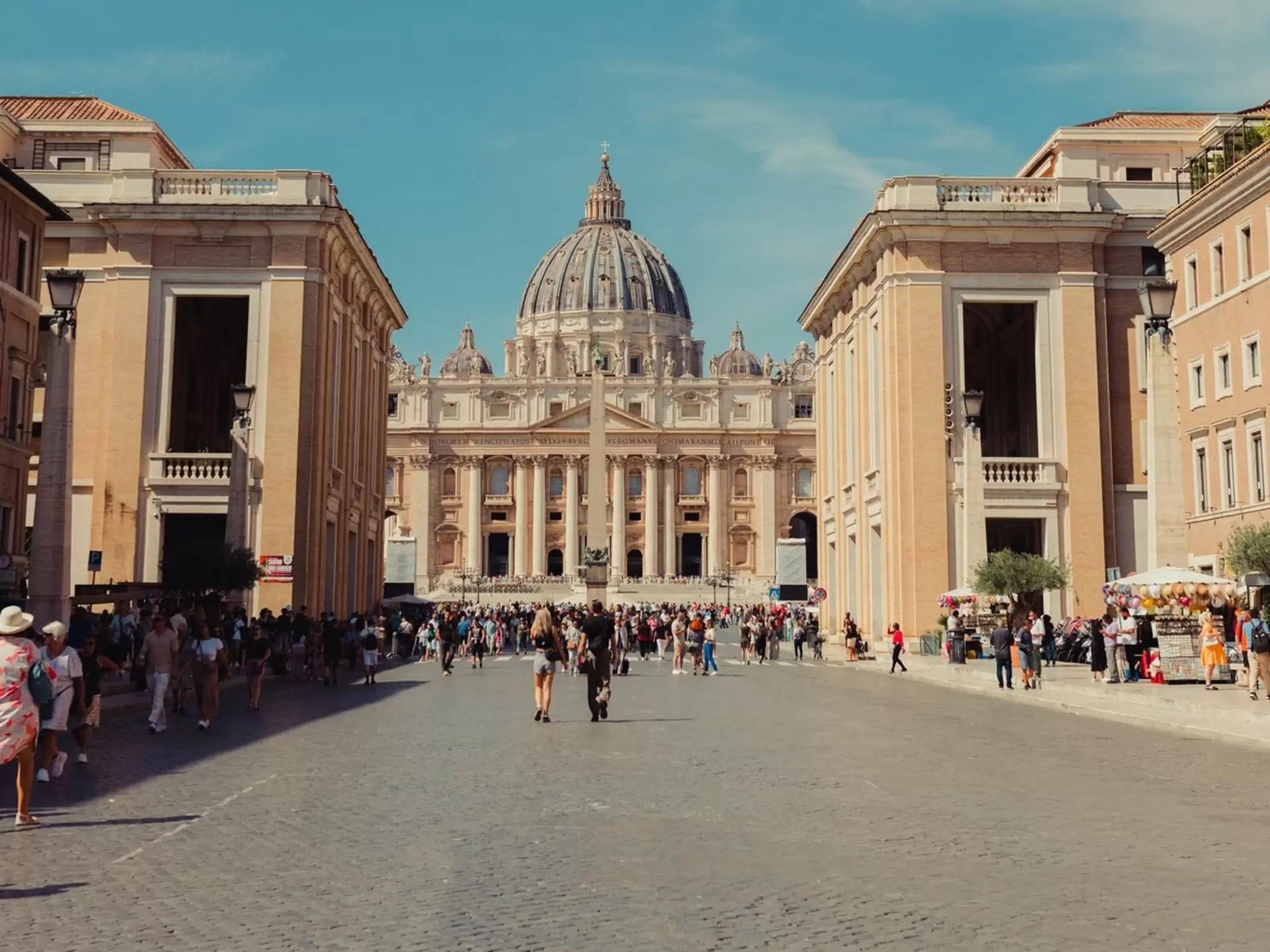 A church with a large dome at the end of a wide pedestrian street.