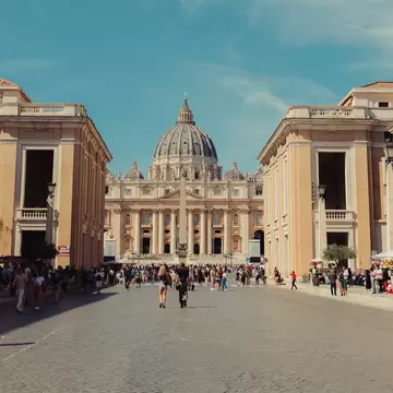 A church with a large dome at the end of a wide pedestrian street.