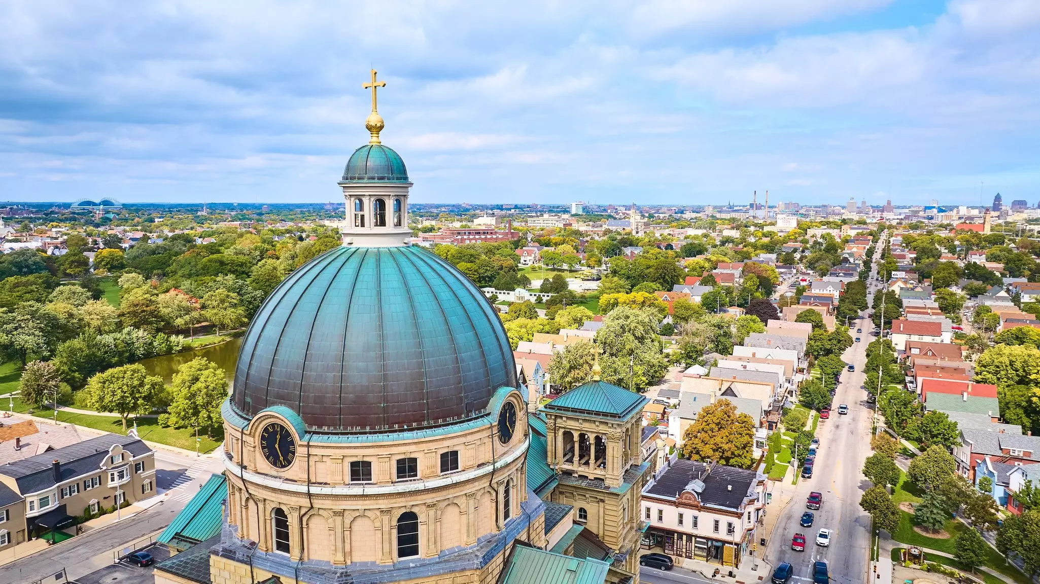 A aerial view of the huge dome of a church and a city skyline beyond.