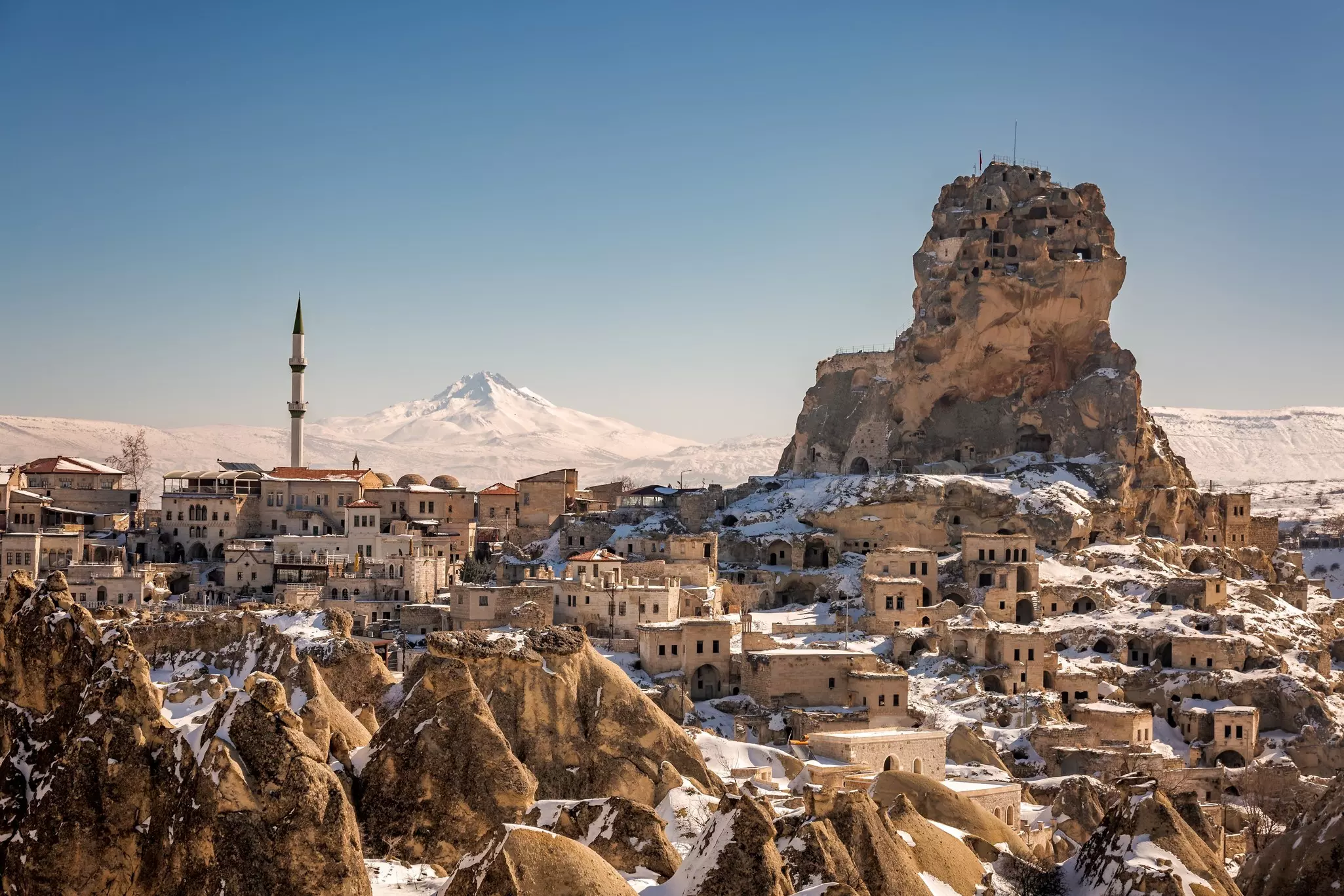 Panoramic view of Ortahisar castle with mosque and old town with a Mount Erciyes in the background at Cappadocia, Turkey