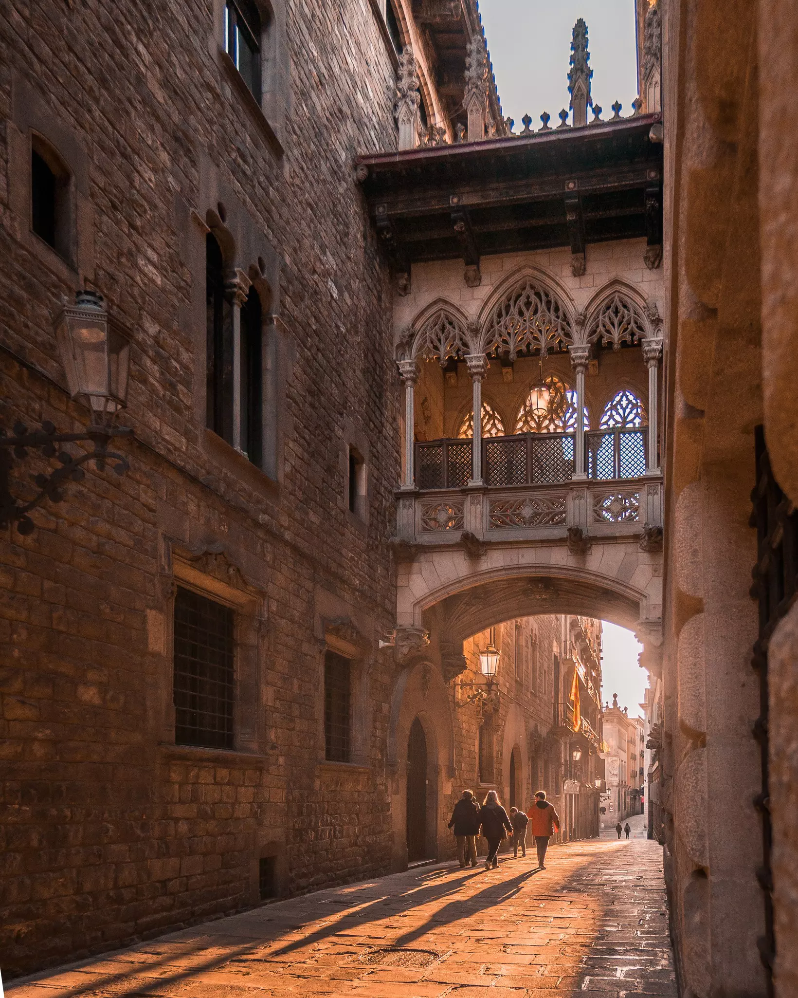 People walking under an arch between gothic style buildings