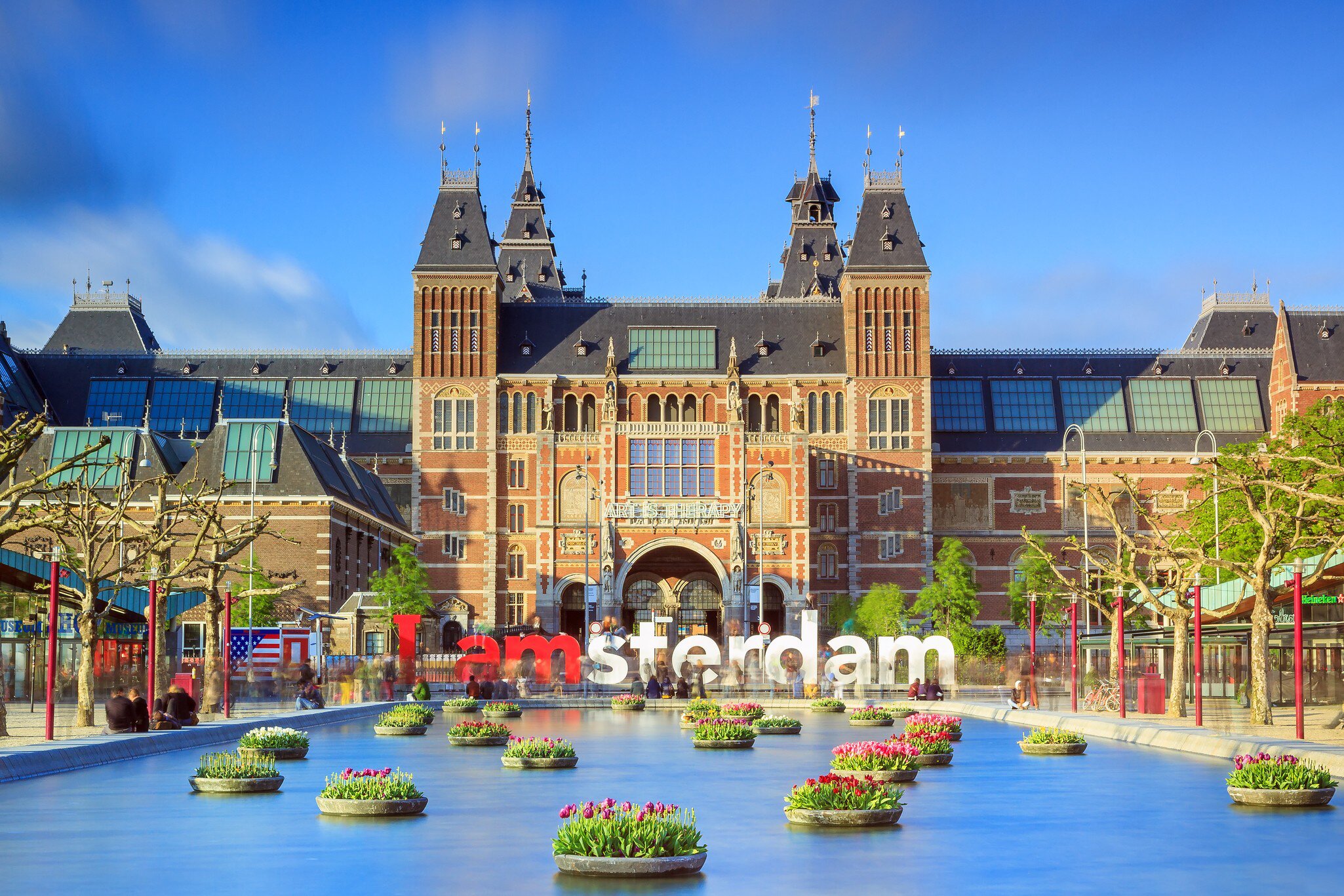 Rijksmuseum with tulips in Amsterdam..NOTE: dated image - "iamamsterdam" sign has been removed from outside museum.
Rijksmuseum, Amsterdam, North Holland, Netherlands, Benelux, Western Europe, Europe, travel, travel destinations, outdoors, daytime, museum, discovery, history, past, incidental people, long exposure, facade, building, architecture, fountain, water, water feature, colorful, flower, plants, text, tree, blue sky