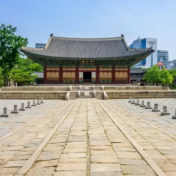 A traditional tiled-roof pavilion with skyscrapers rising behind it.