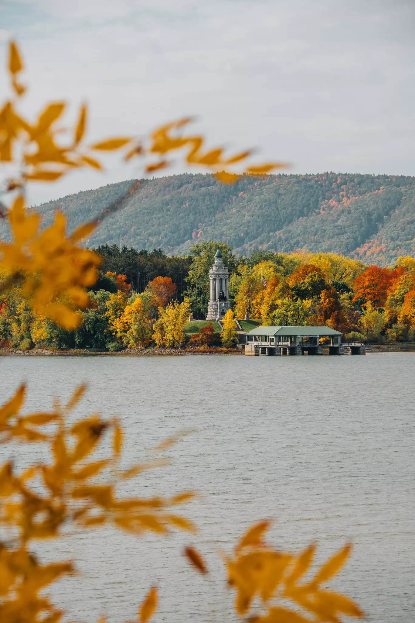 A lighthouse and a dock on a lake surrounded by fall foliage