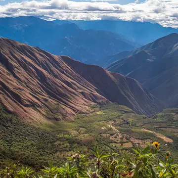 A mountainous area on a sunny day with blue sky and big clouds.