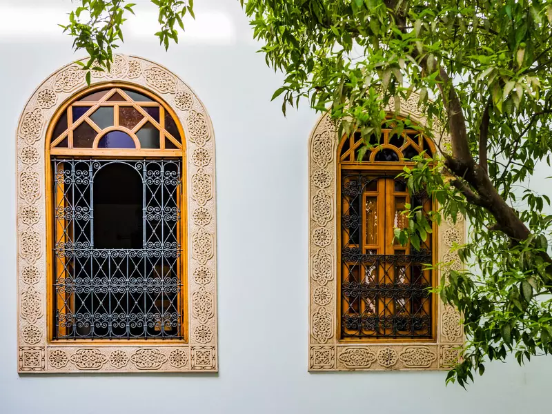 Two arched windows with decorated grills and carvings around the perimeter.