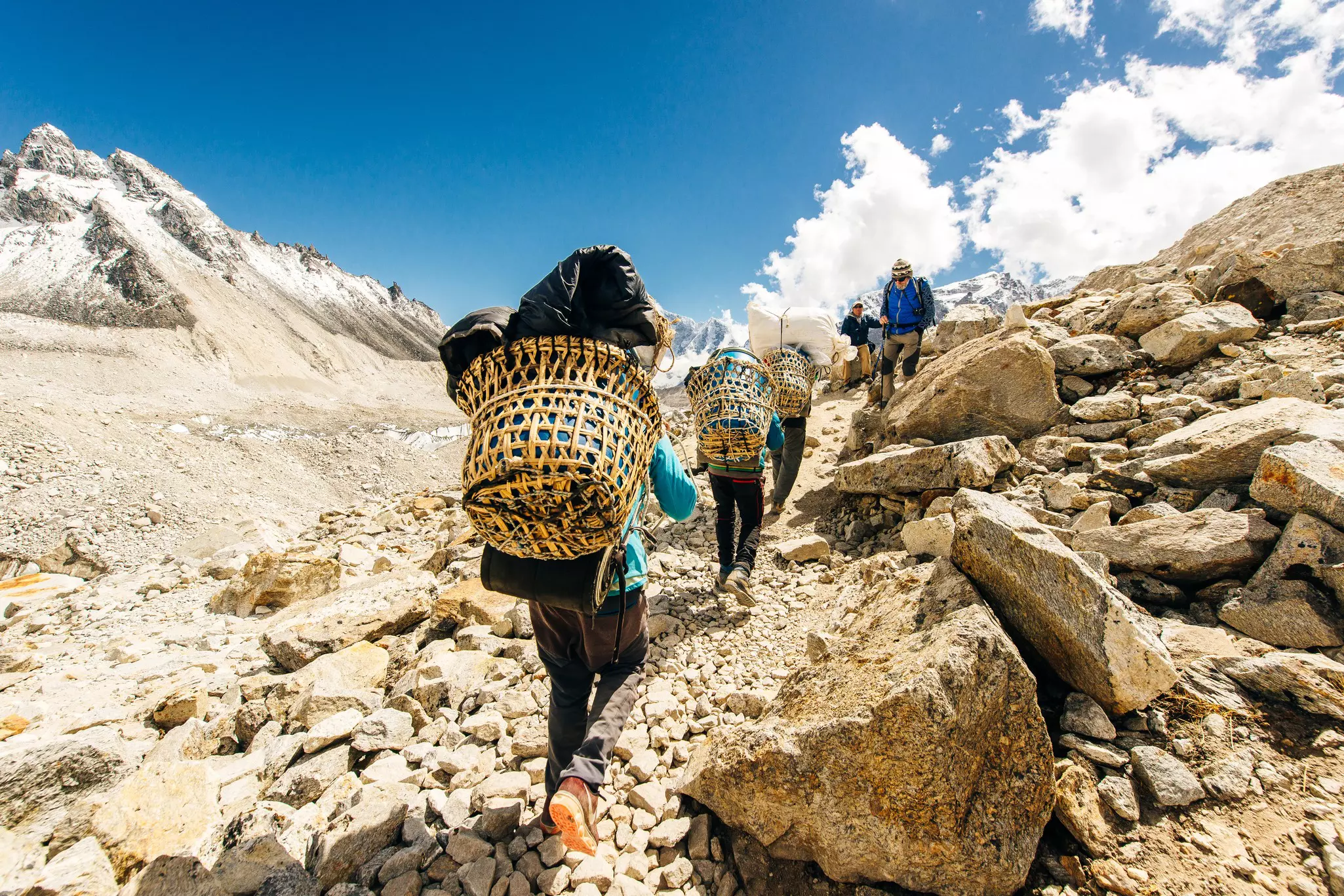 Porters carry loads in baskets on a rocky trail in the Khumbu region near Everest Base Camp, Nepal.