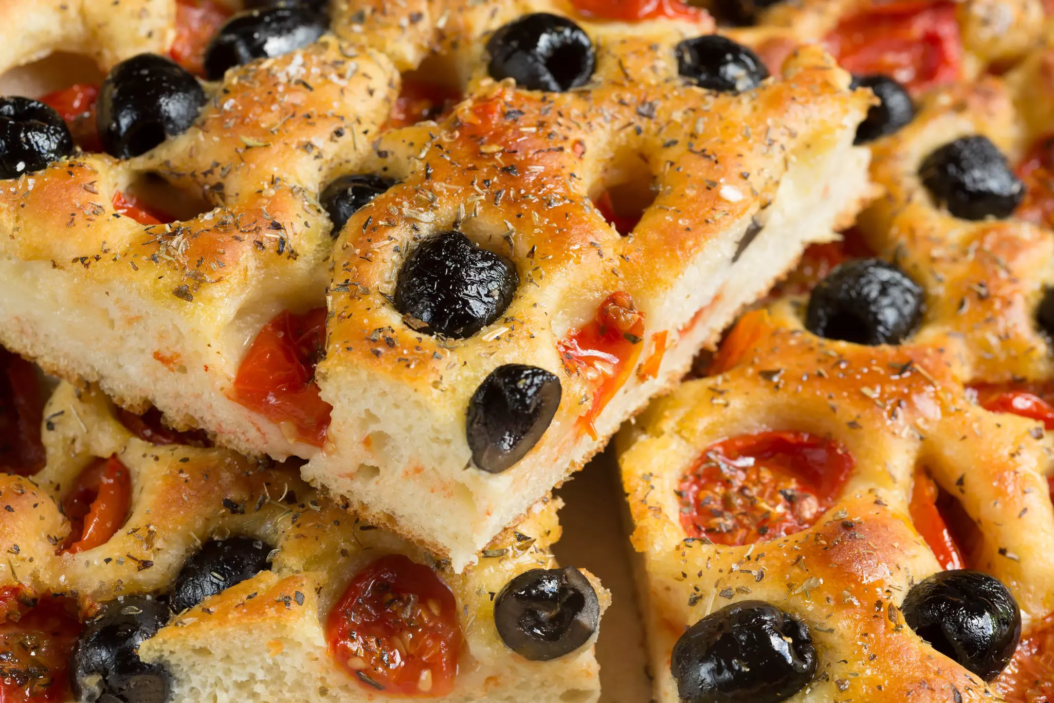 Fresh slices of focaccia barese with olives and tomatoes in Puglia, Italy.