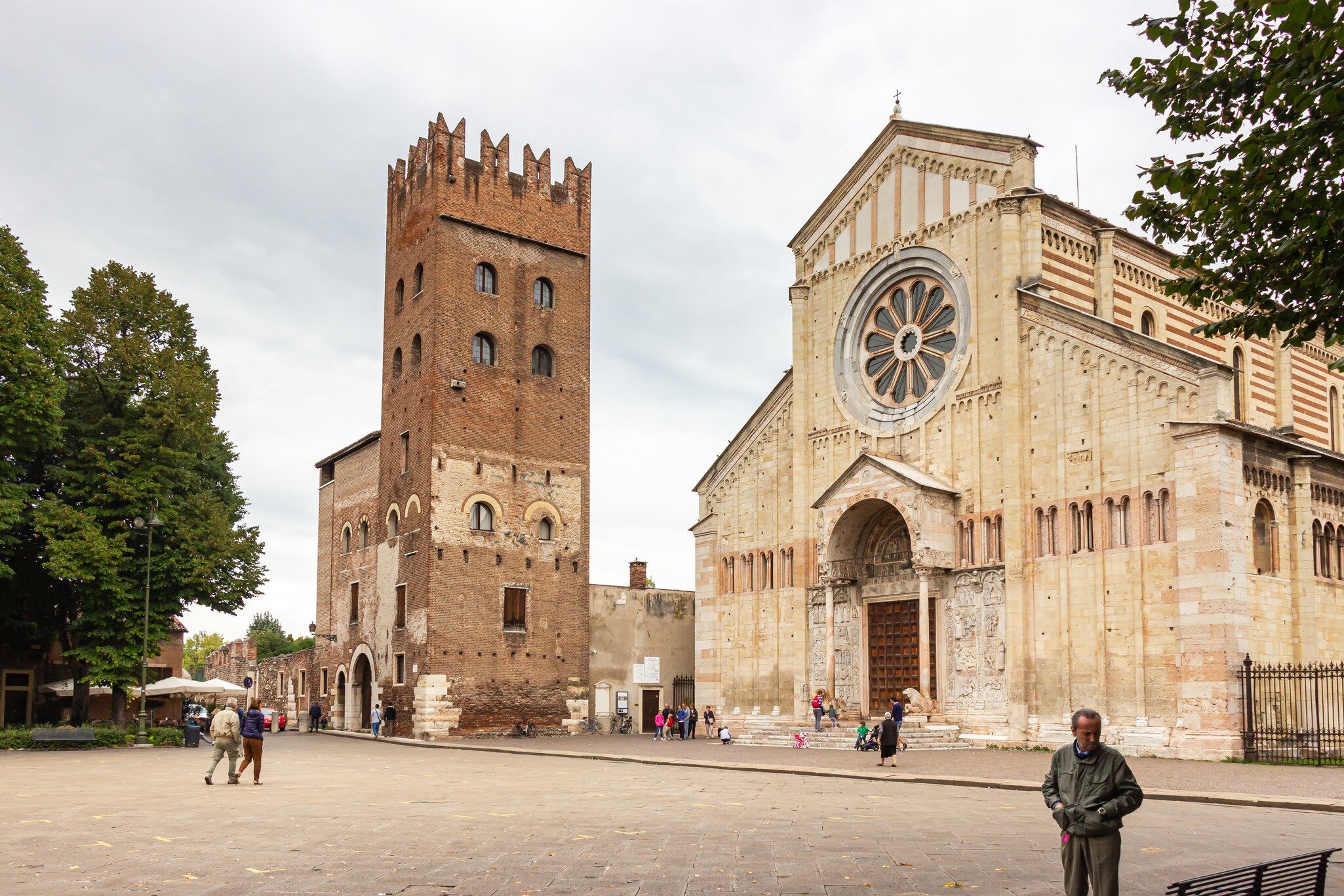 Tourists and passersby walk by the Basilica di San Zeno Maggiore  in Verona, Italy.