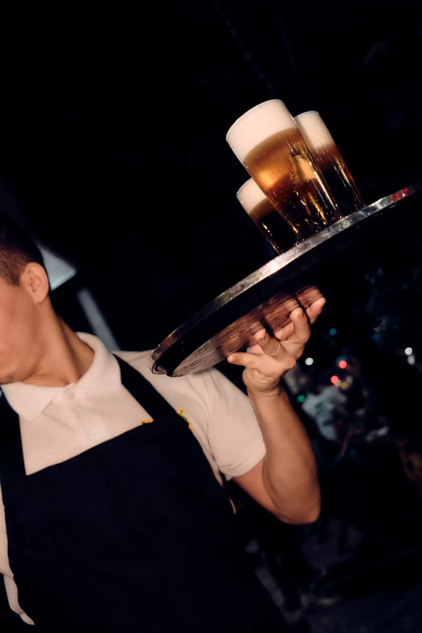 A man holding glasses of beer on a tray.