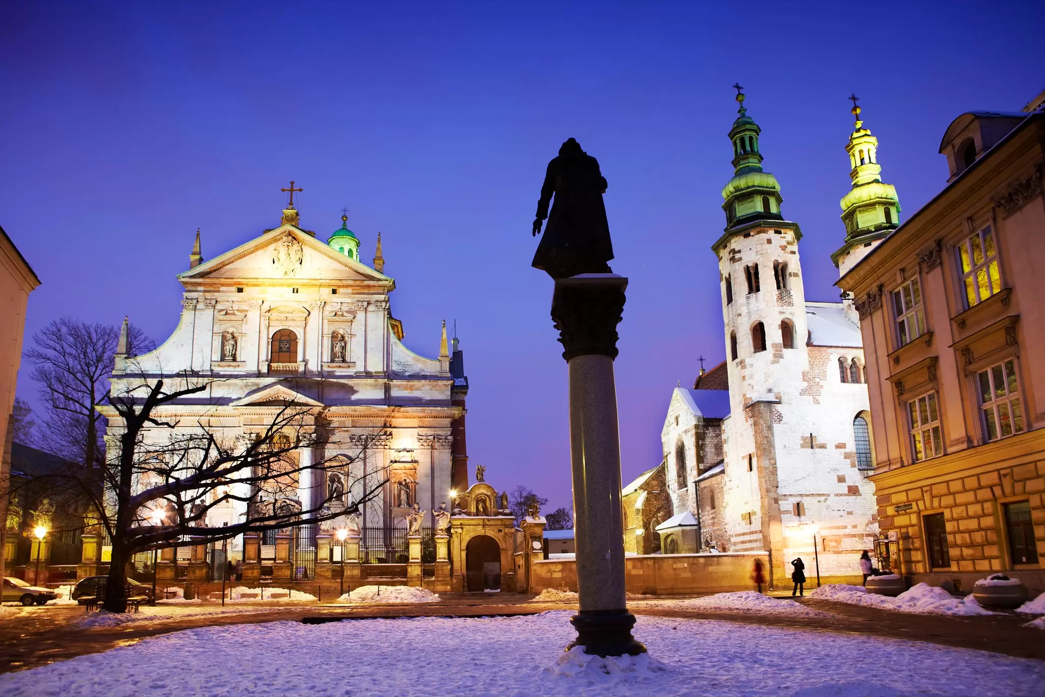 Snow fills the main market square in Kraków, Poland, with the buildings illuminated at night. 
