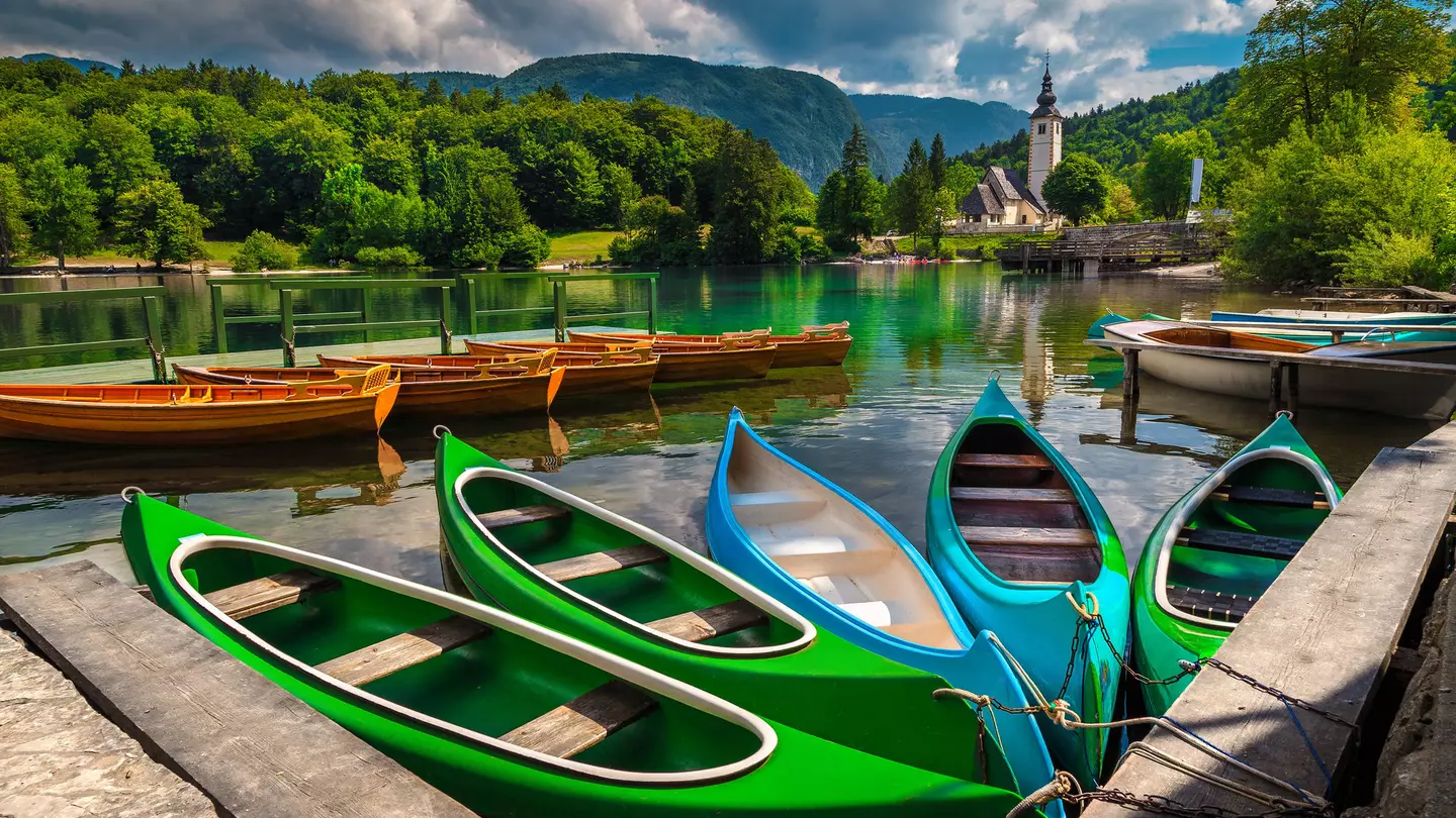 Anchored,Colorful,Canoes,,Kayaks,And,Wooden,Boats,On,The,Lake.