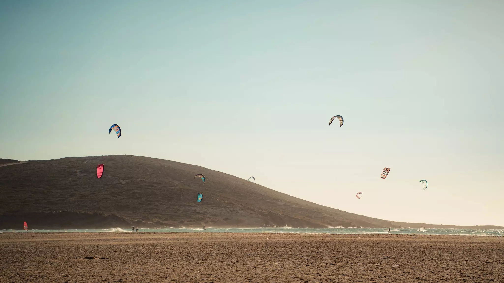 People kitesurfing on the beach.