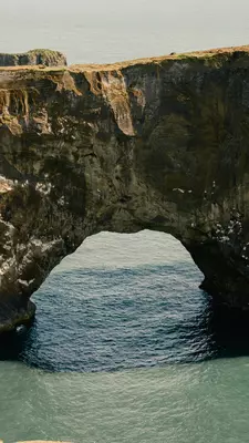 A natural rock archway over water.