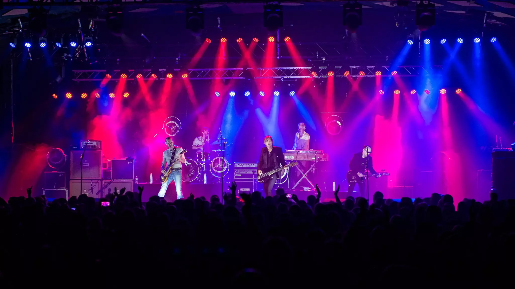 A band performing under colored lights on a stage in Glasgow, Scotland.