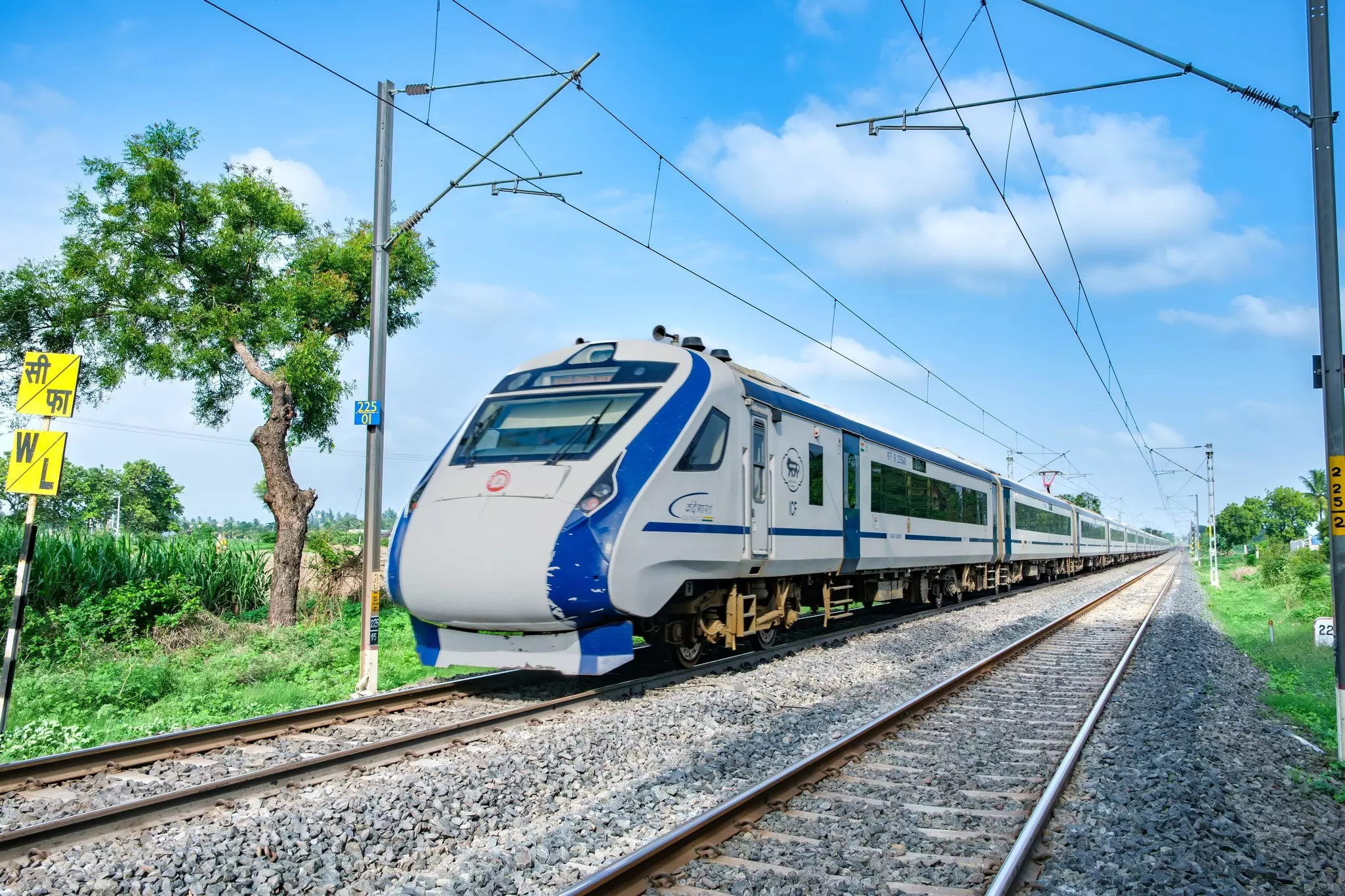 A blue and silver modern train on a track with overhead wires.