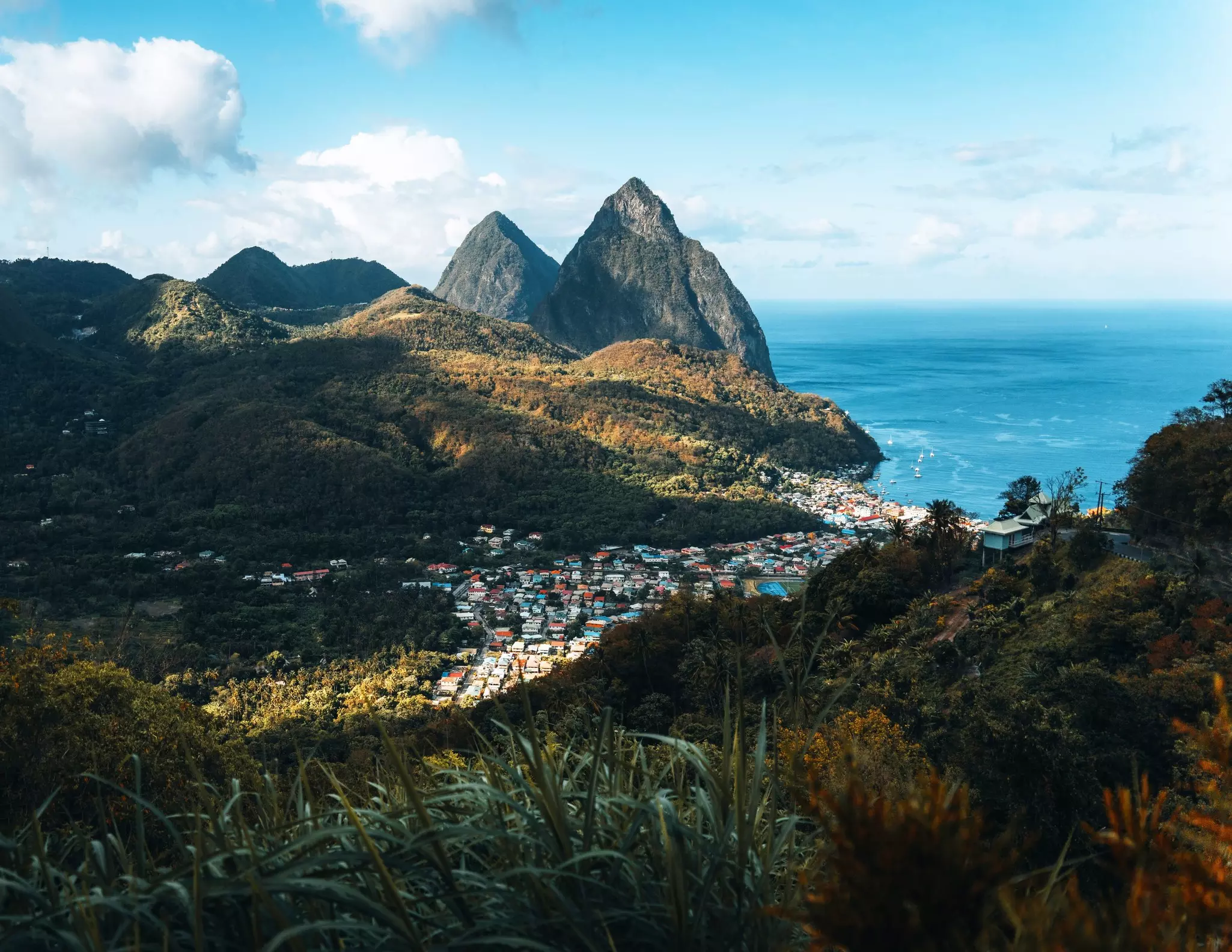 Soufrière, St Lucia, with the Pitons in the background and blue Caribbean waters on a partly cloudy day