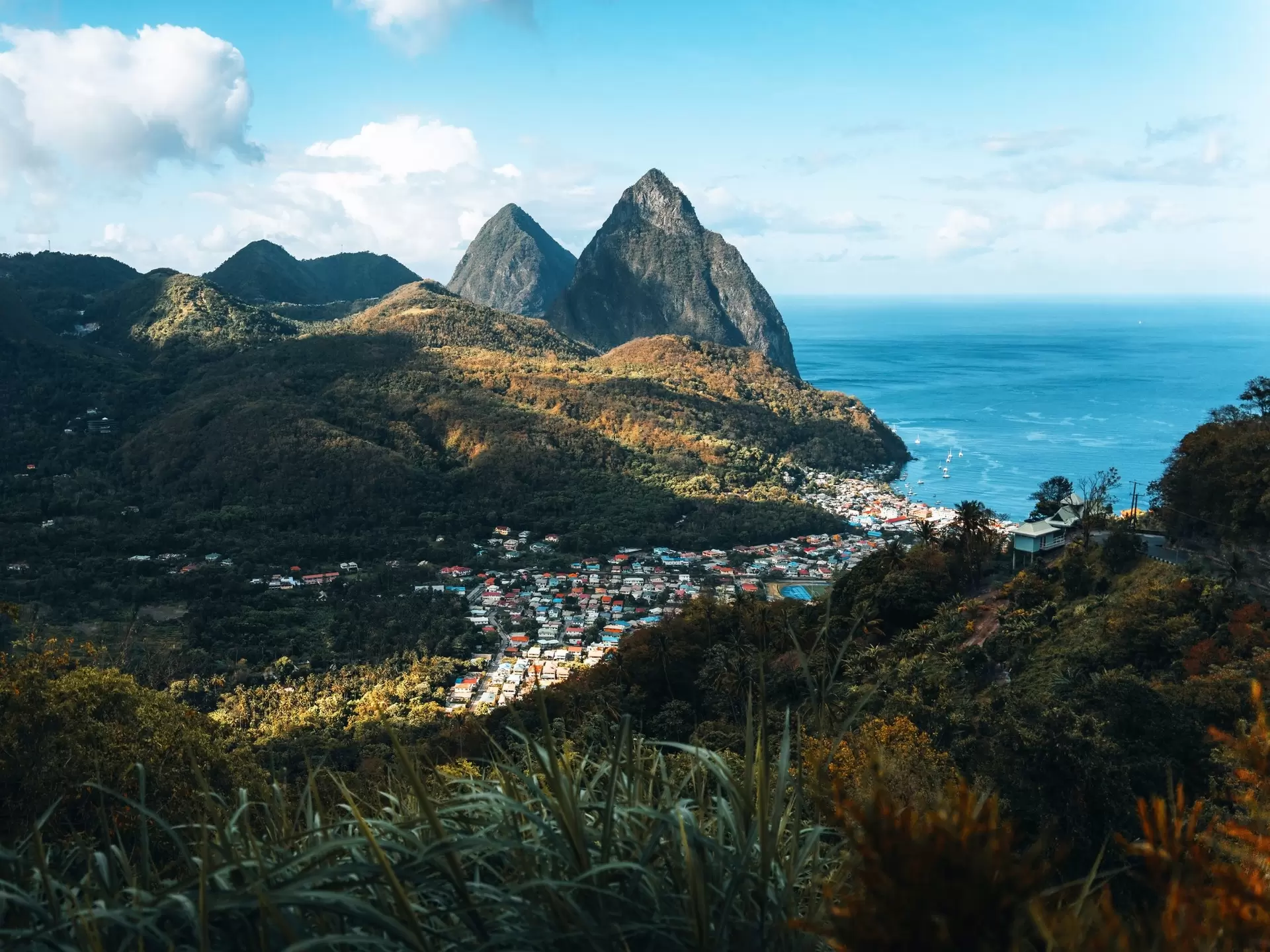 Pointed mountain peaks by turquoise water; a town is at the base by the water.