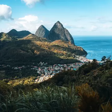 Pointed mountain peaks by turquoise water; a town is at the base by the water.