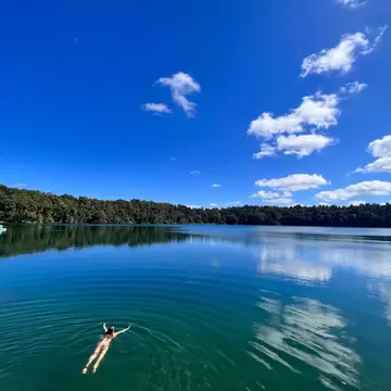 Aerial landscape view of Australian woman swim in Lake Eacham, a popular lake of volcanic origin on the Atherton Tableland in tropical far north of Queensland Australia.