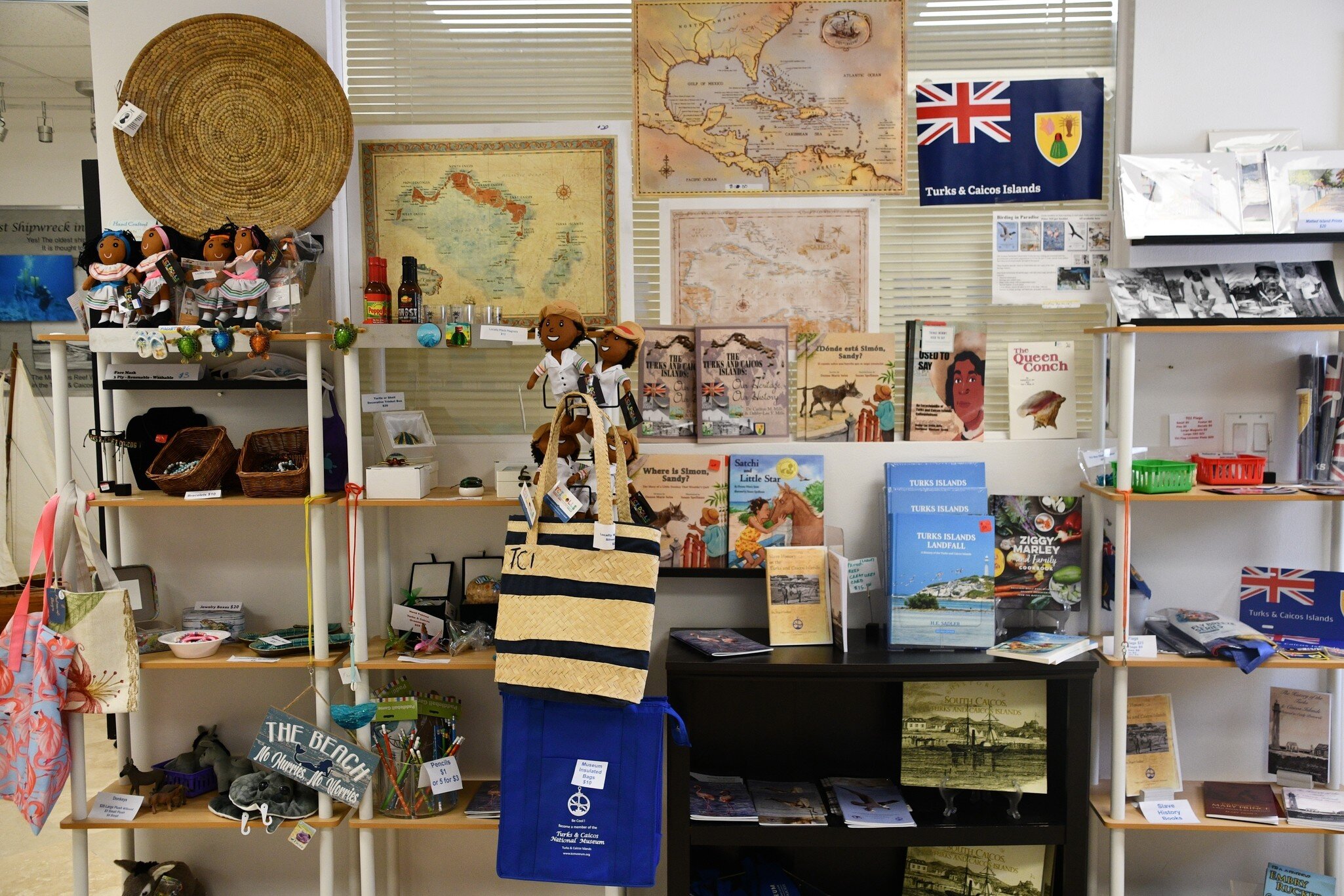 Shelves of local books, dolls, maps and woven bags in the gift shop of the Turks & Caicos National Museum.