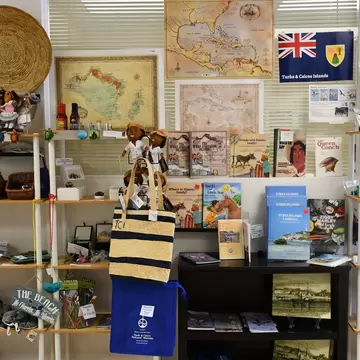 Shelves of local books, dolls, maps and woven bags in the gift shop of the Turks & Caicos National Museum.