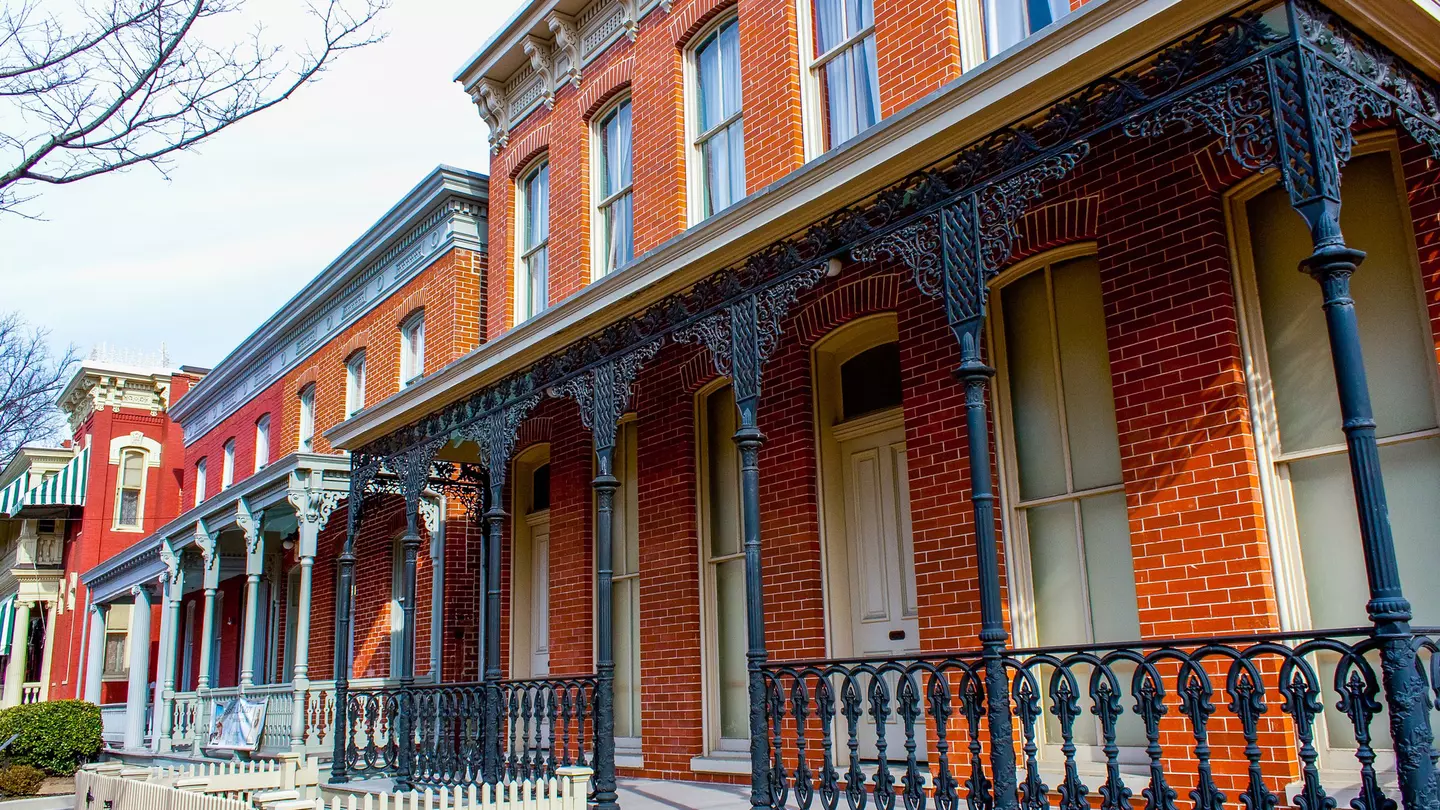A red-brick property with ornate wrought-iron railings at its entrance