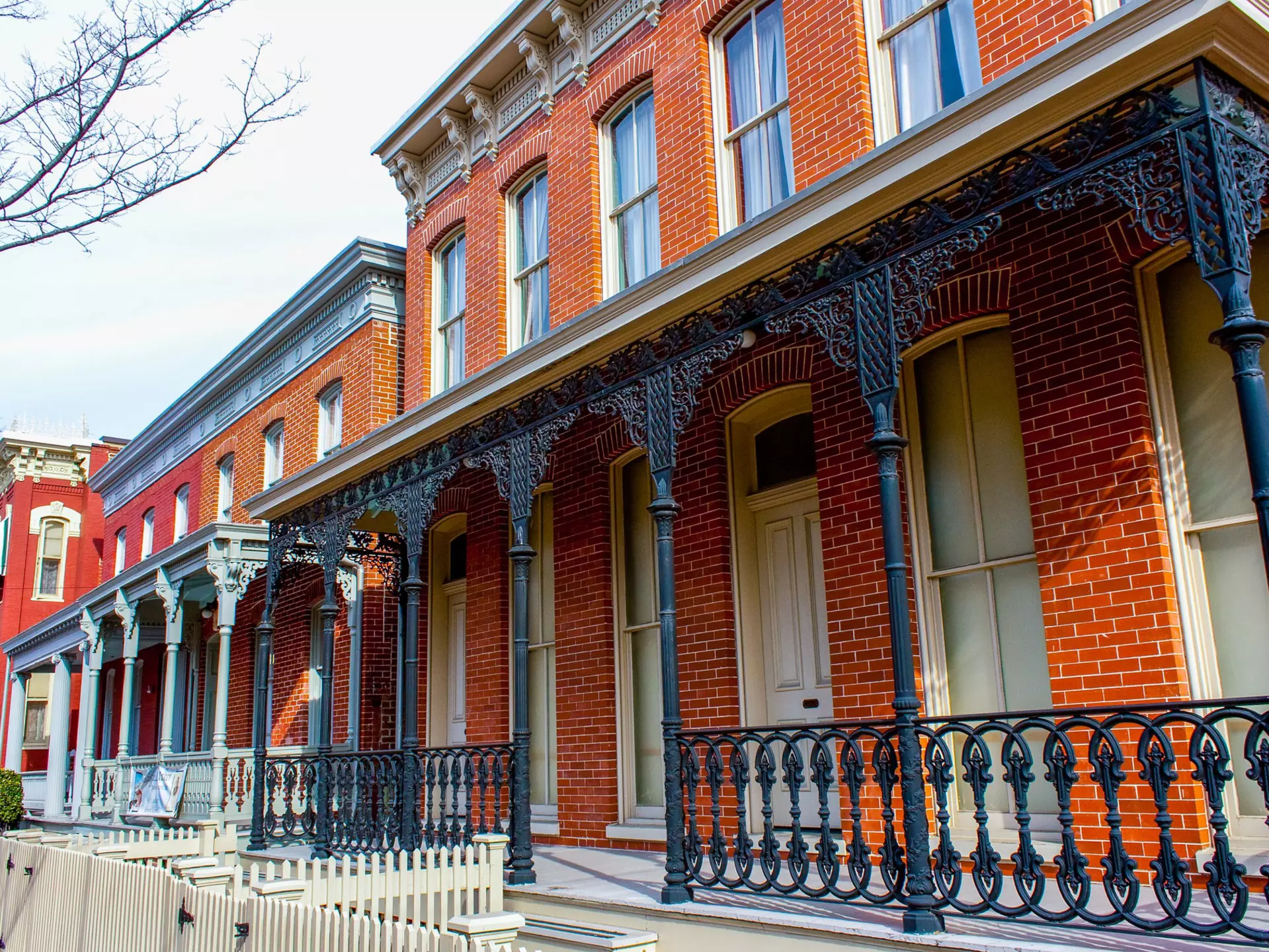 A red-brick property with ornate wrought-iron railings at its entrance