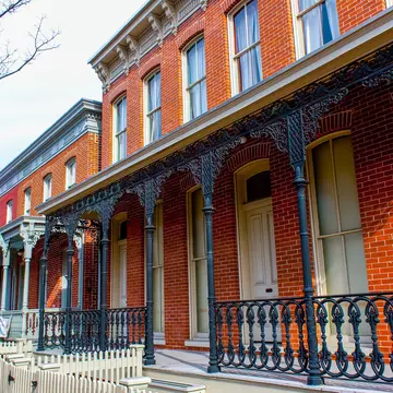 A red-brick property with ornate wrought-iron railings at its entrance