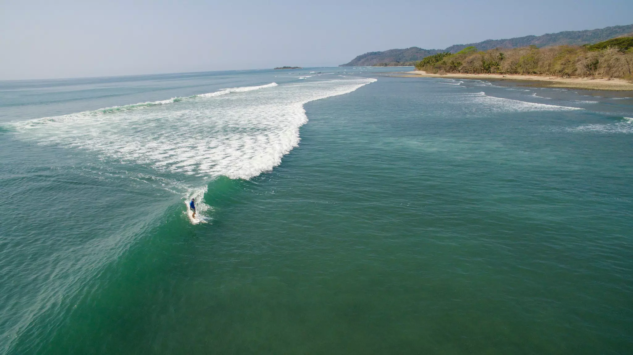 Aerial view of a surfer on a wave off of the shores of Santa Teresa in Costa Rica. 