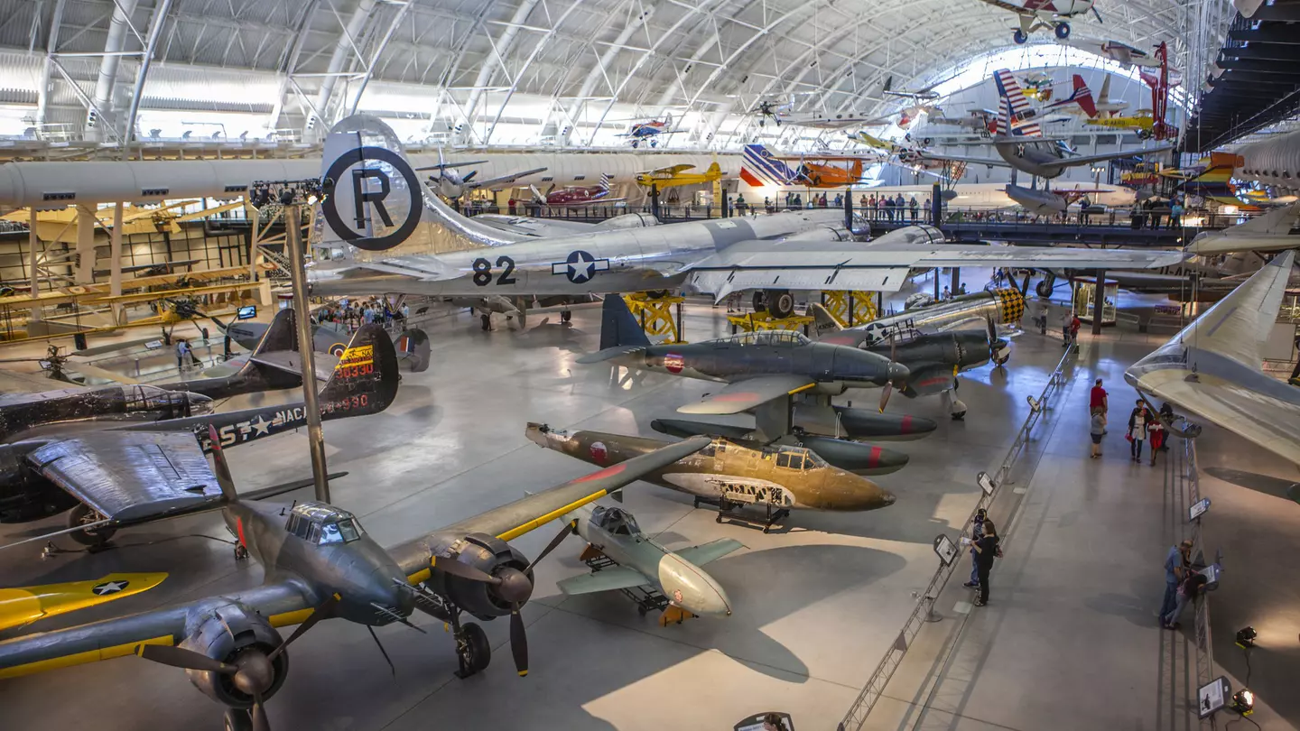 A huge aircraft hangar displaying many different types of plane, rocket and engine. People are following the walkways between exhibits