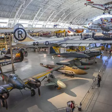 A huge aircraft hangar displaying many different types of plane, rocket and engine. People are following the walkways between exhibits