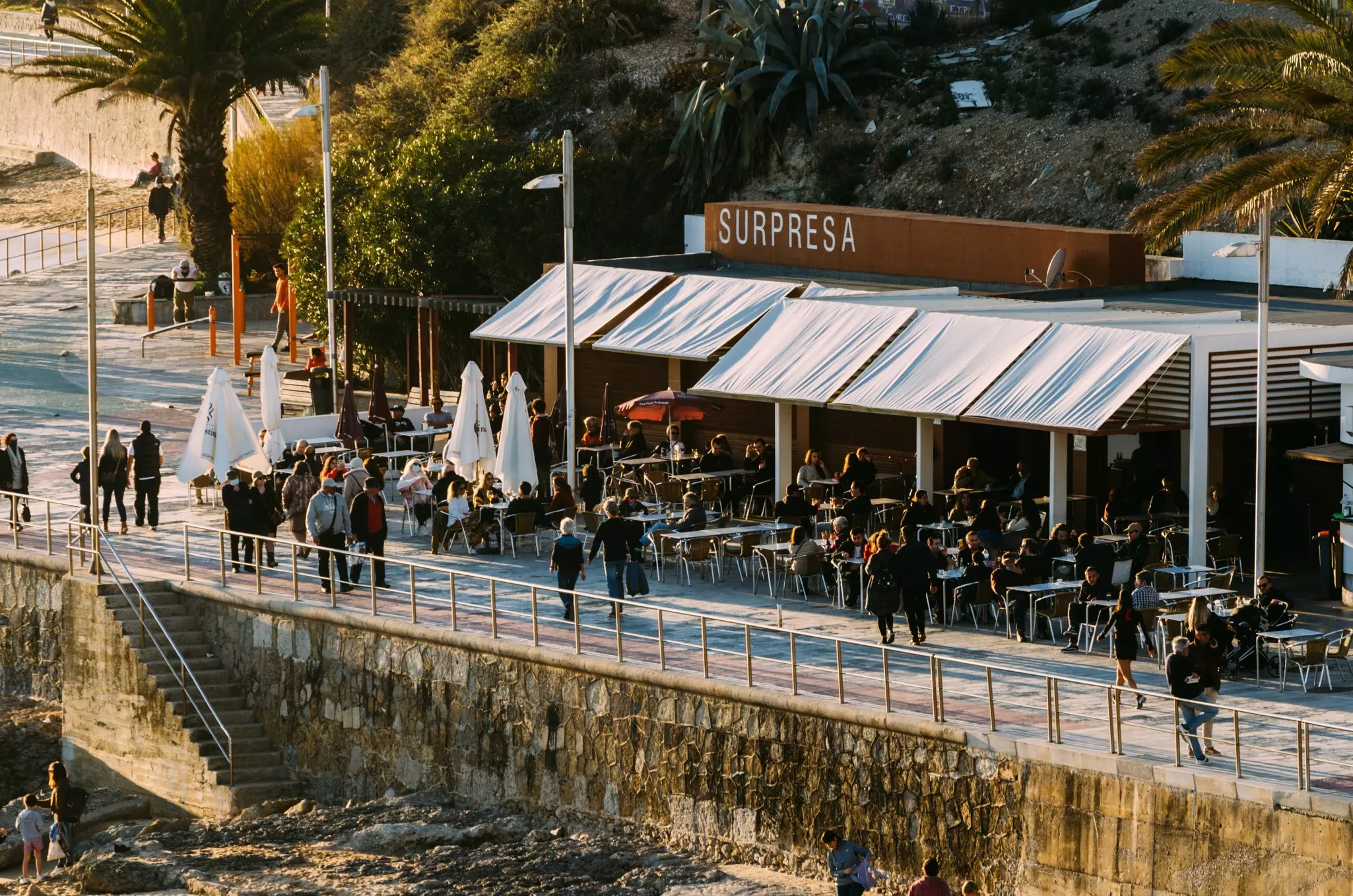 A wide view of a restaurant along a seafront promenade.
