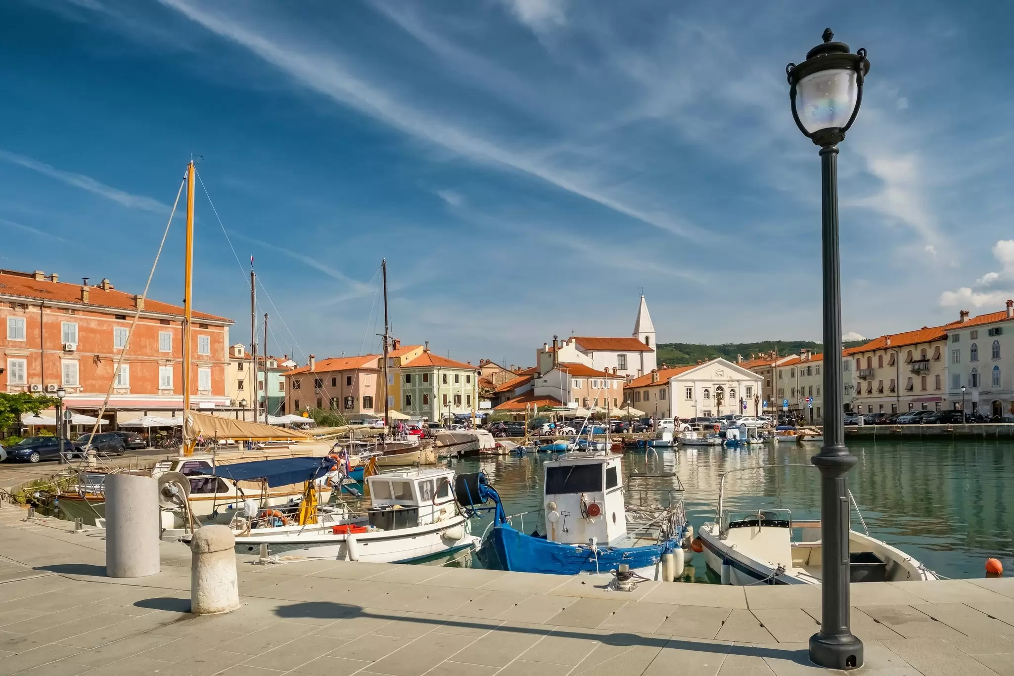 White and orange buildings around a small harbor with boats moored in it.