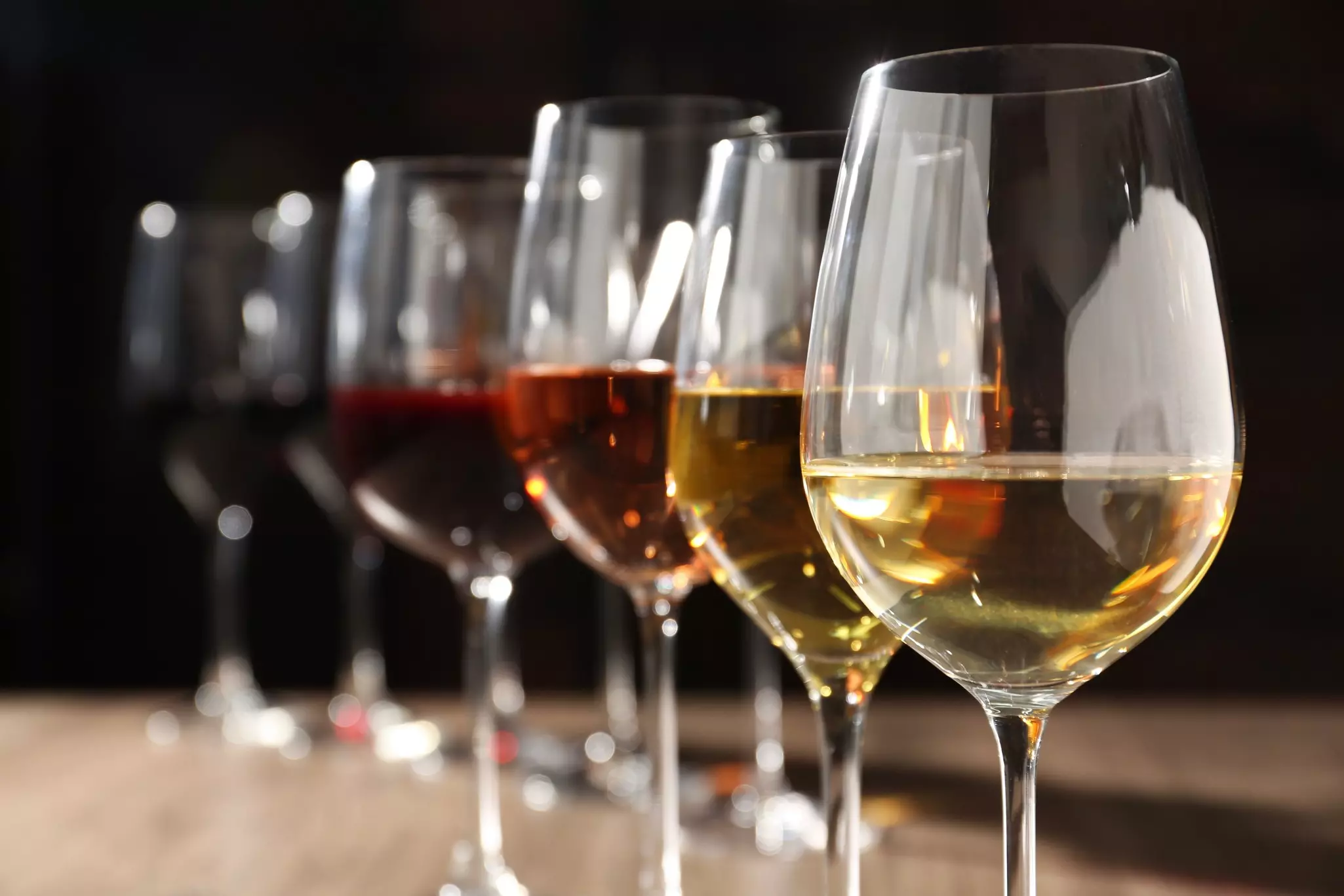 Different tasty wines in glasses against blurred background