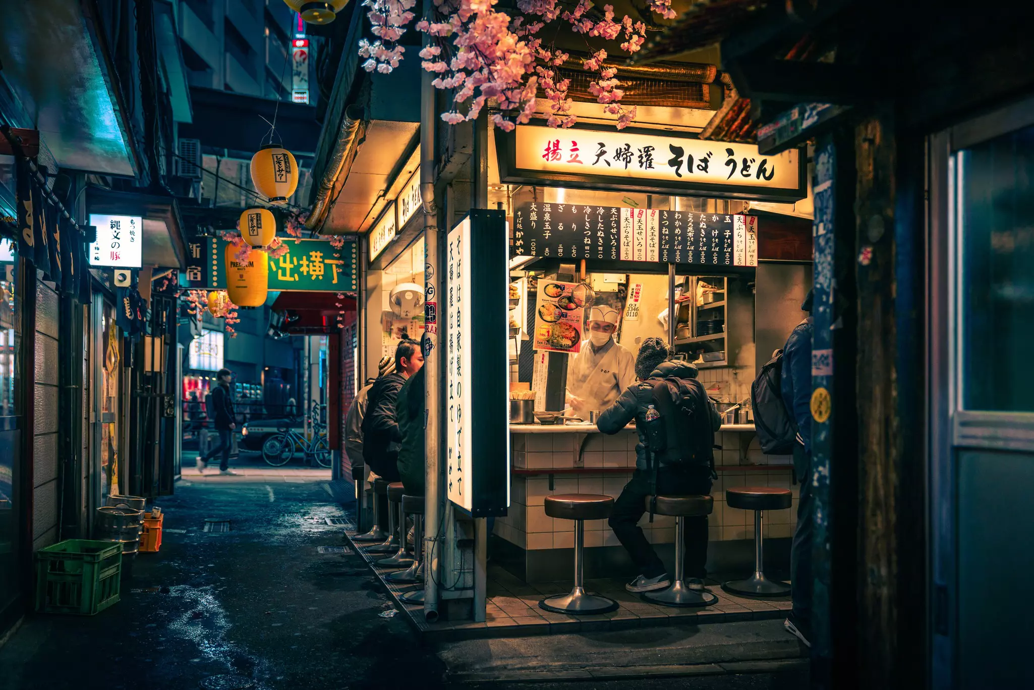 A small bar in an alleyway with Japanese signage and yellow lanterns