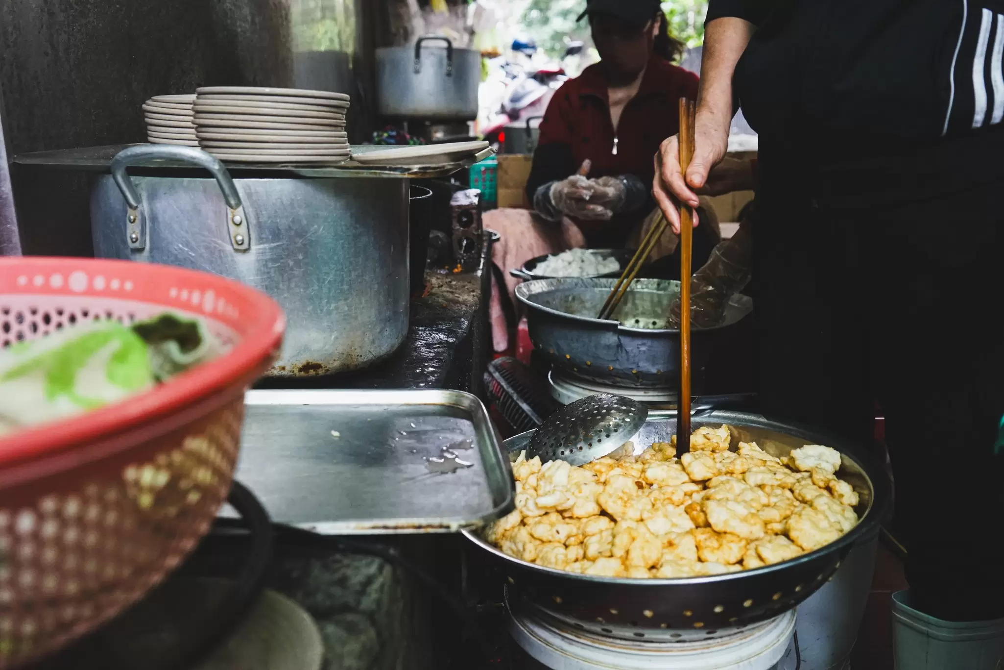 Staff cooking in a kitchen in Halong City Vietnam, one wears a face mask.