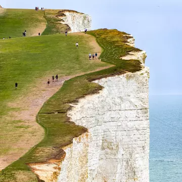 canto-naft59o2 - Walkers follow the towering chalk cliffs at Beachy Head in the South Downs. Richard Whitcombe/Shutterstock