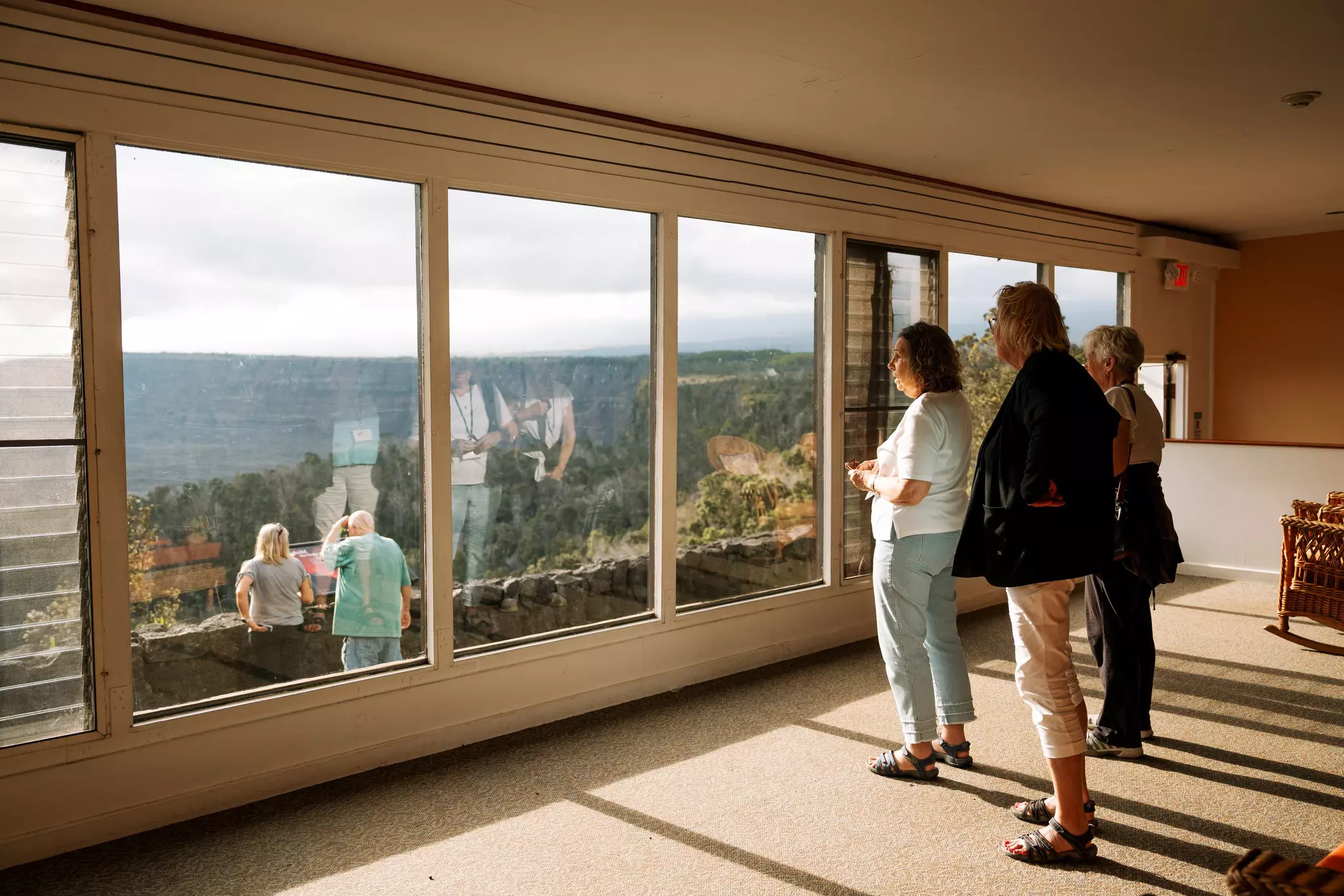People stare out of a large window overlooking a crater