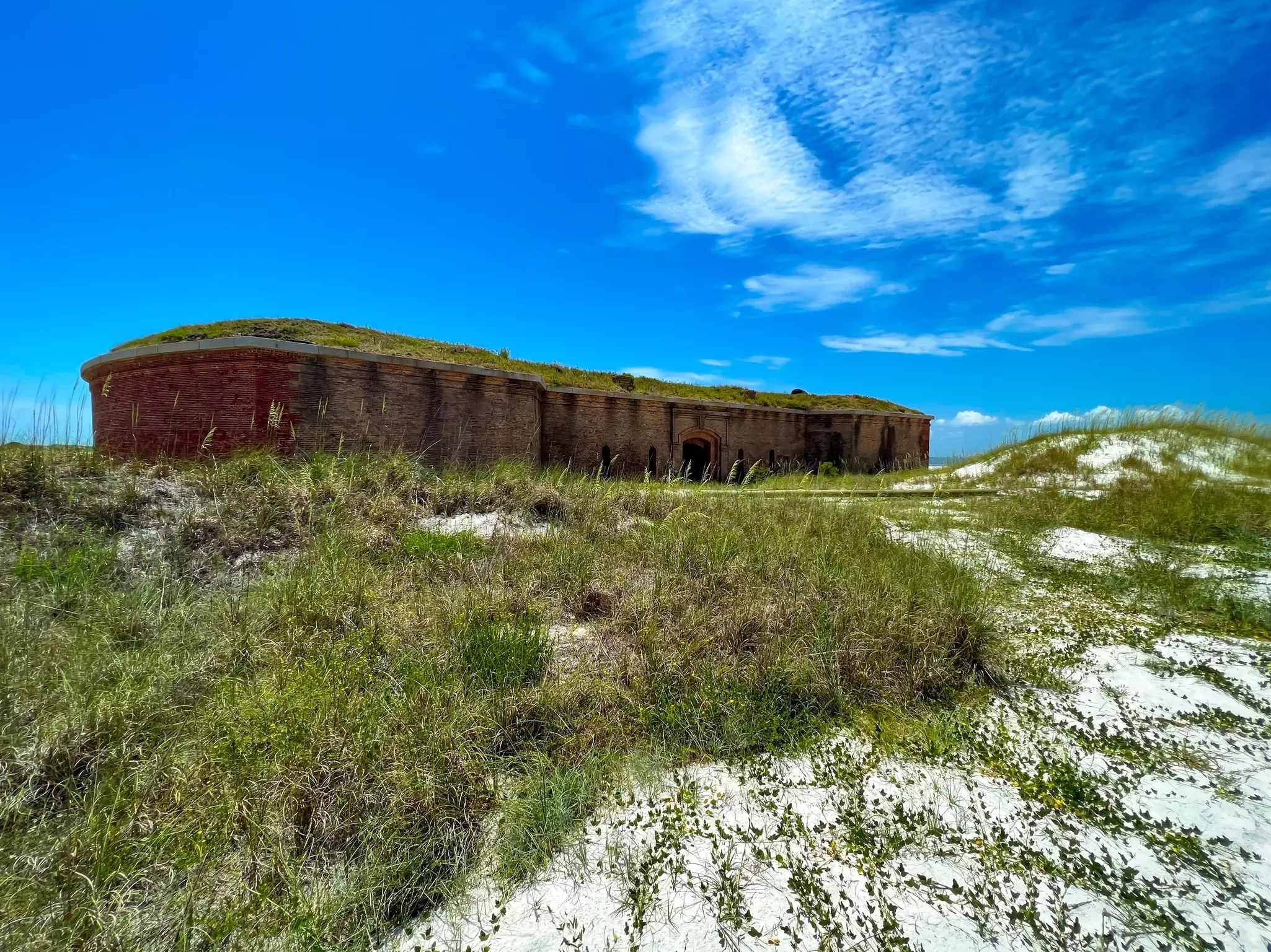 A historic fort is pictured in front of beach dunes.