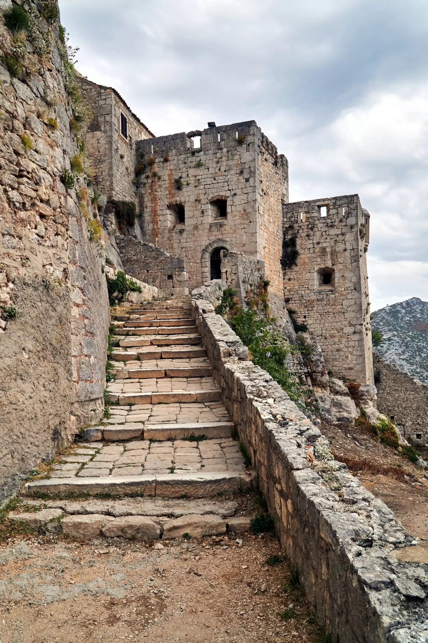 A huge stone fortification at the top of a steep, narrow path