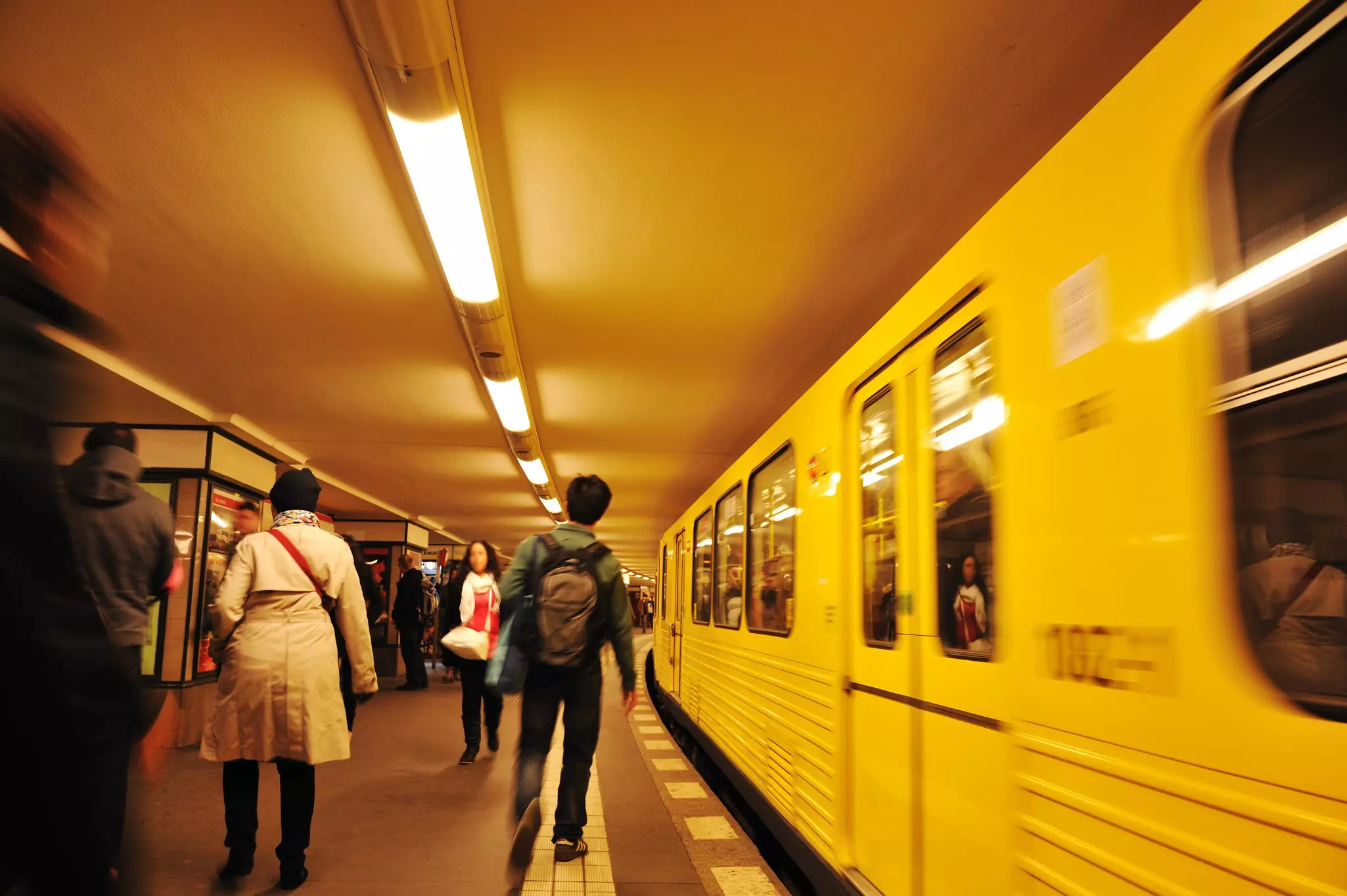 Young woman looks at photos on camera while waiting in metro station for train