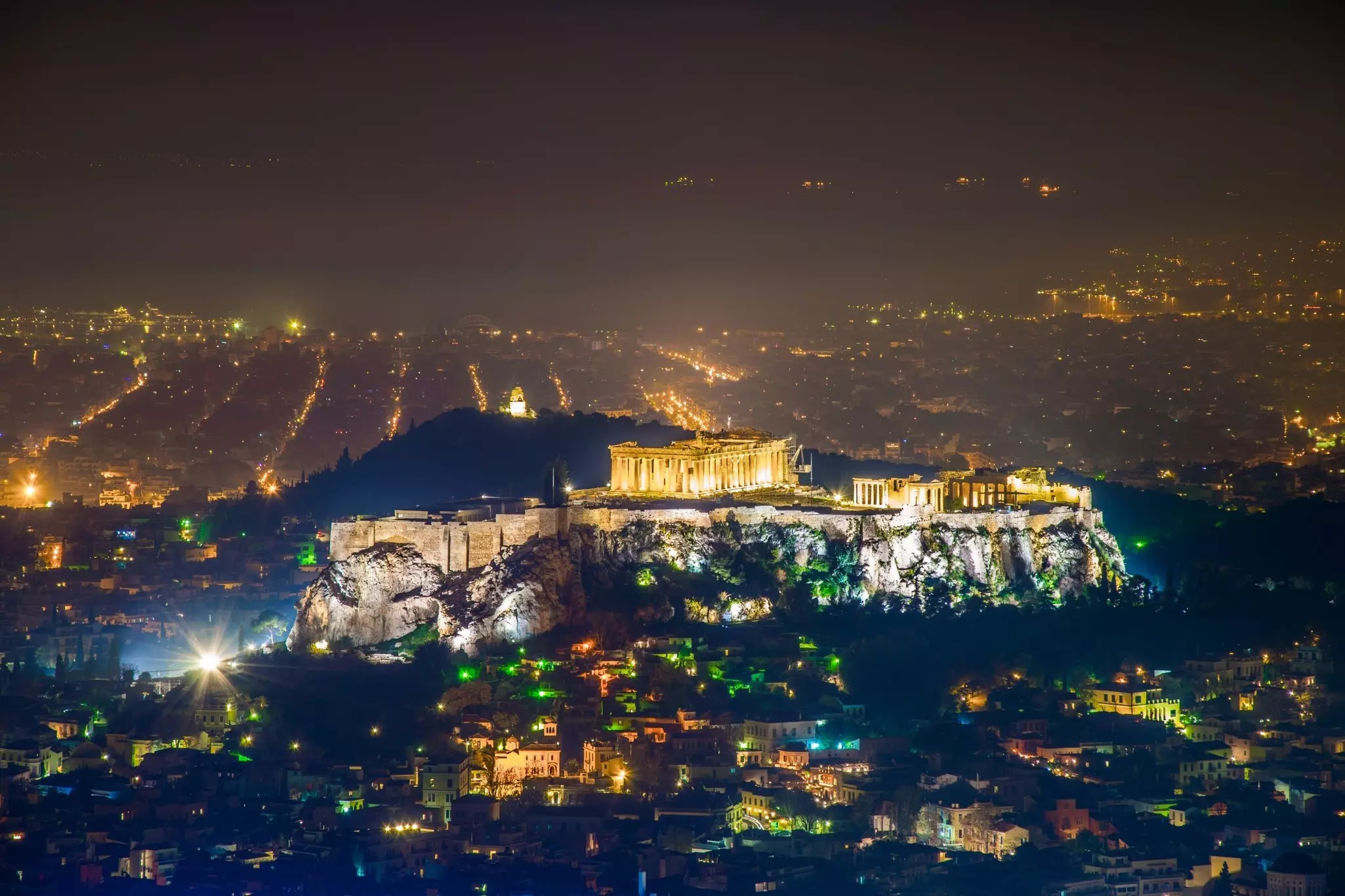 Aerial of Athens cityscape and the Acropolis monument at night.