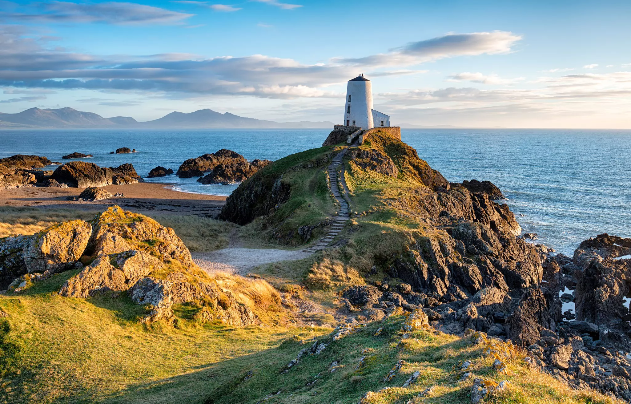 A small white lighthouse on a rocky outcrop of an island.