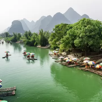 Tourist bamboo rafts on the Yulong River in Yangshuo County. Scenic karst mountains are visible in background.