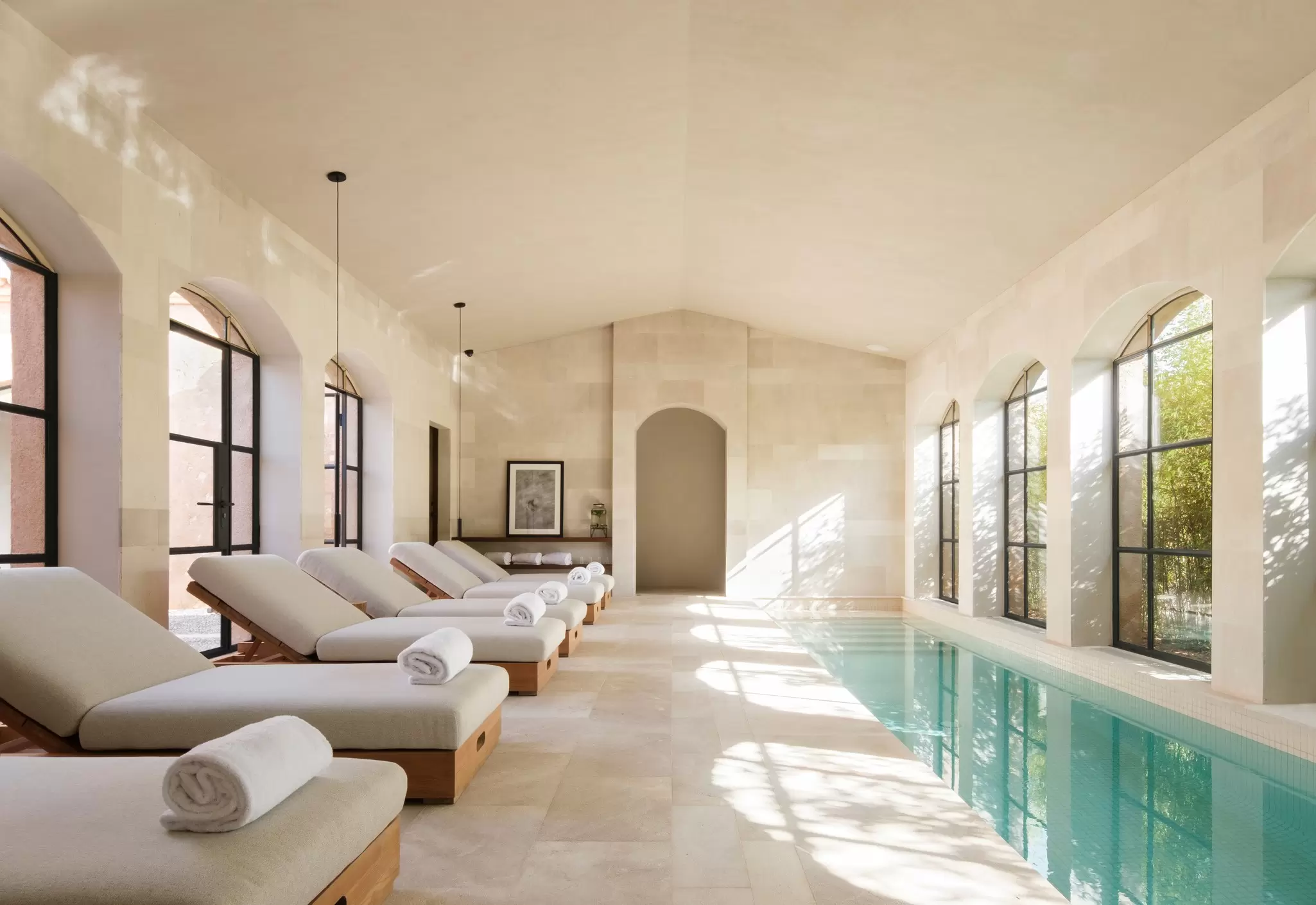 A row of loungers at the edge of a narrow indoor pool: the spa at Can Ferrereta, Santanyí, Mallorca, Spain