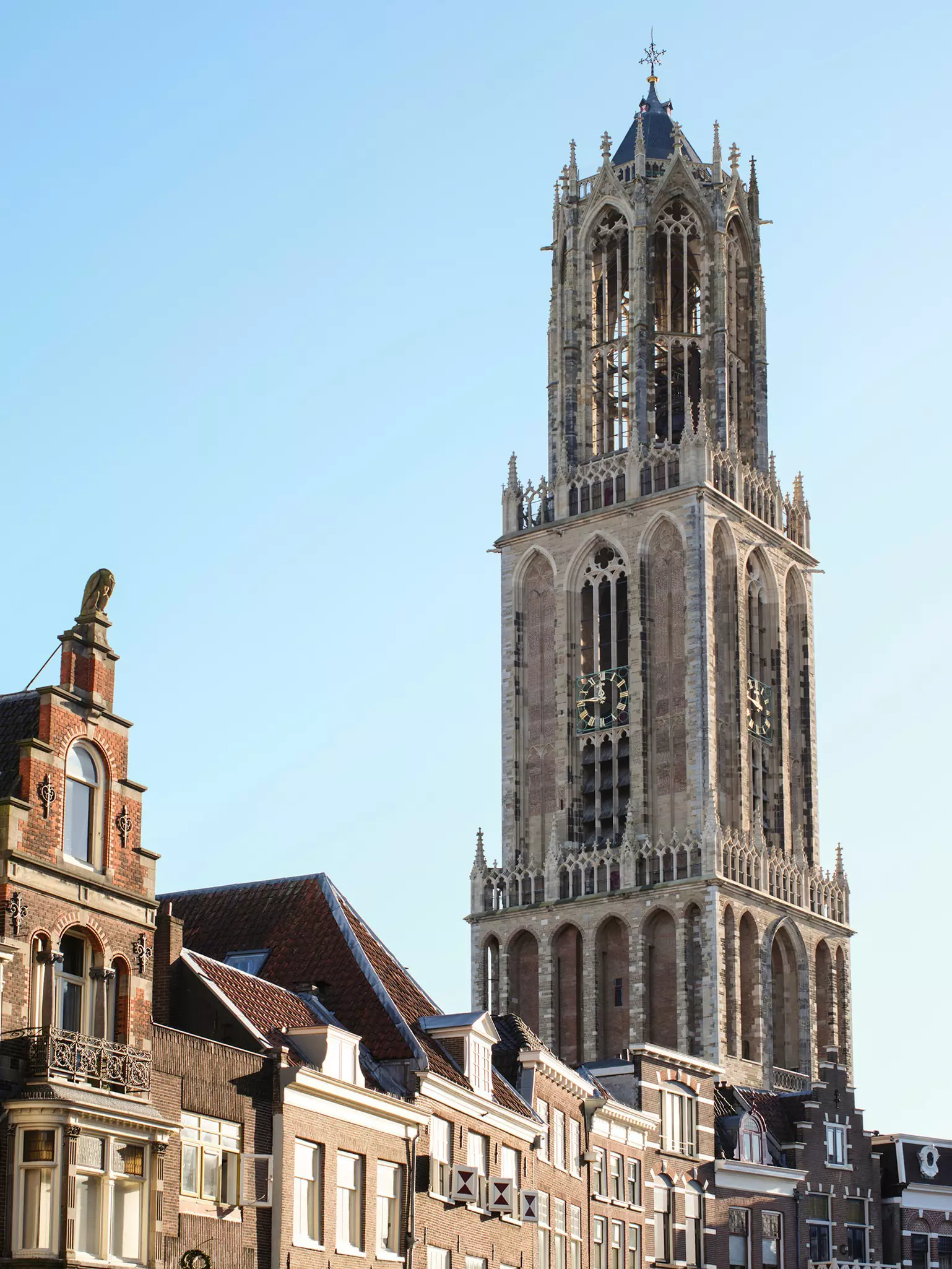 An impressive Gothic bell tower with a clock standing tall over a city.