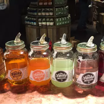 Jars containing colored liquors to taste are displayed on the counter of a distillery.
