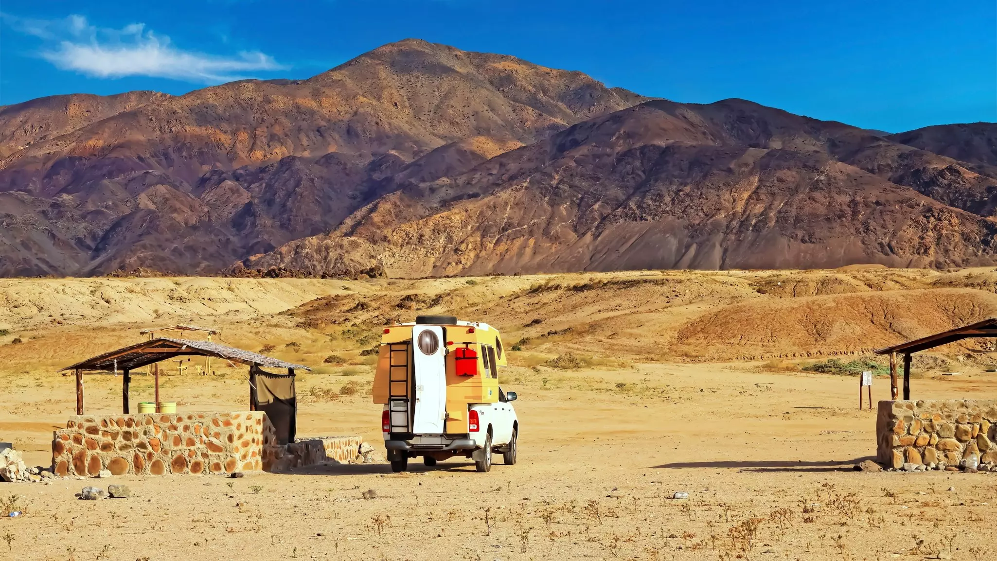 A camper can sits in the orange desert looking out at a mountain. Atacama, Chile