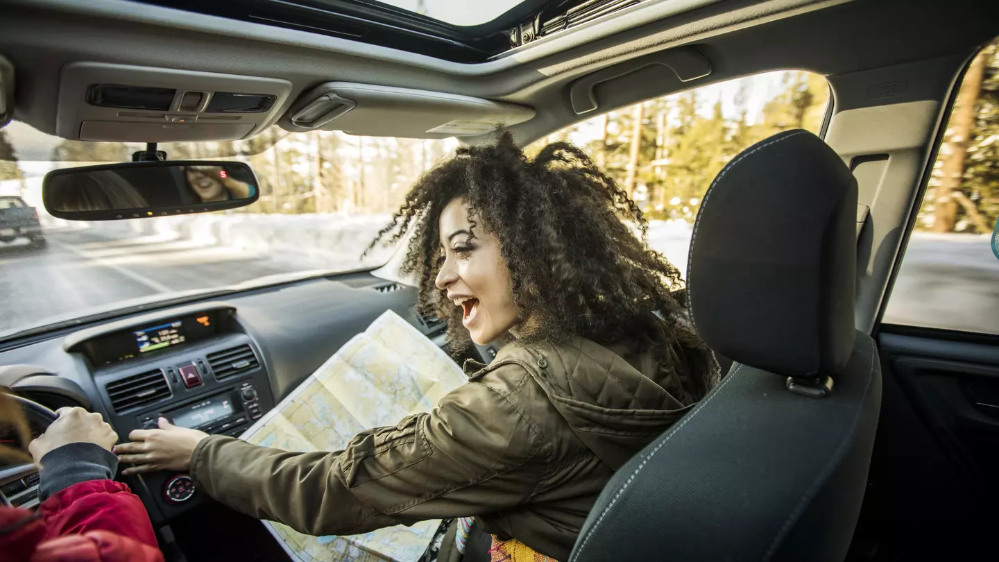 Woman driving car, friend in passenger seat looking at map
